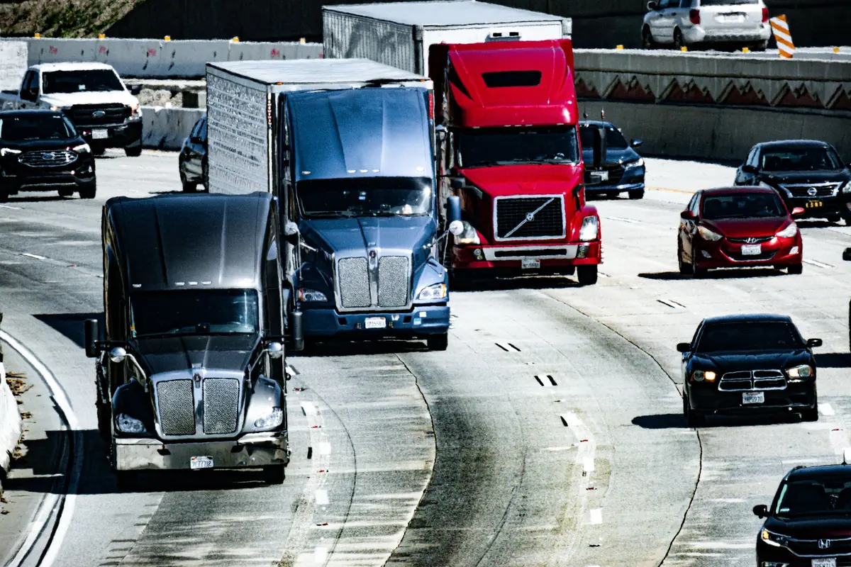 Highway tractors moving with traffic on a busy multi-lane freeway